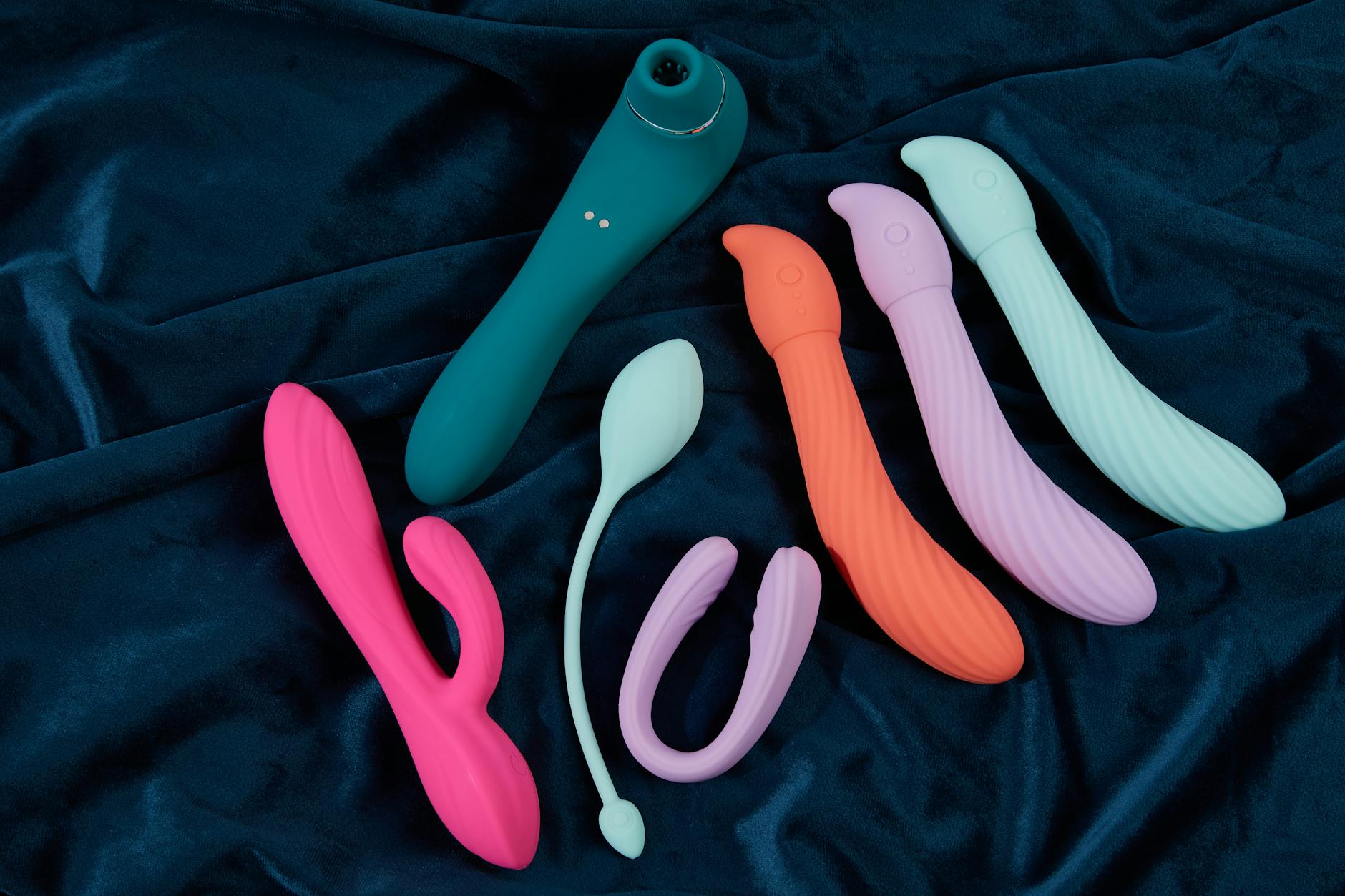 Collection of hypoallergenic silicone vibrators and toys displayed on soft white fabric