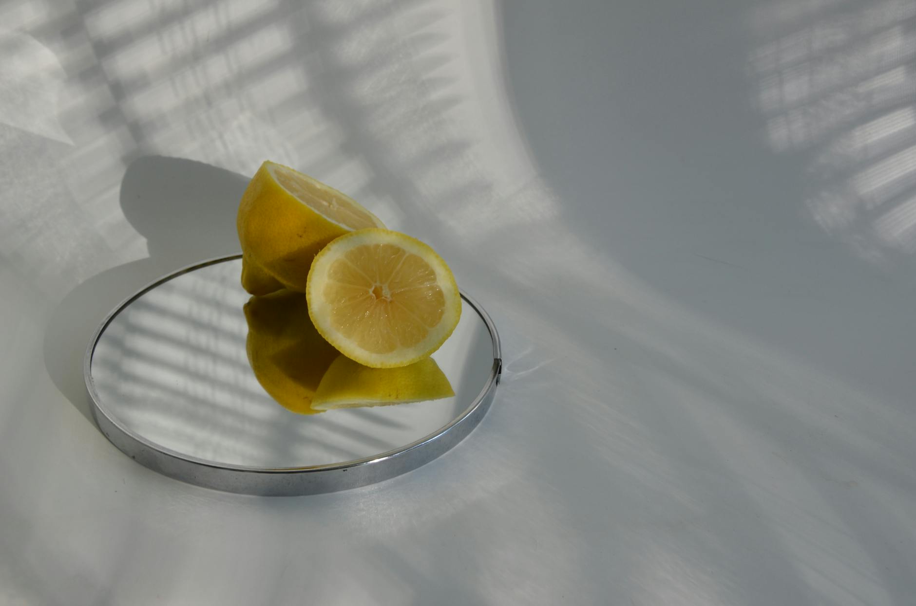Sliced lemons on a mirror with soft shadows, representing fresh beginnings and pleasure.