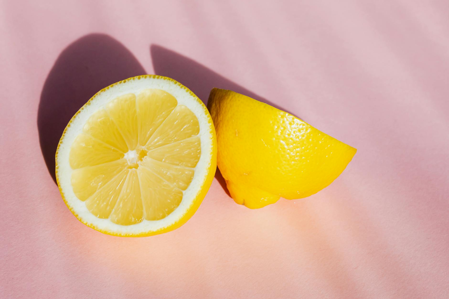 Fresh cut lemon halves on a pink background in bright sunlight