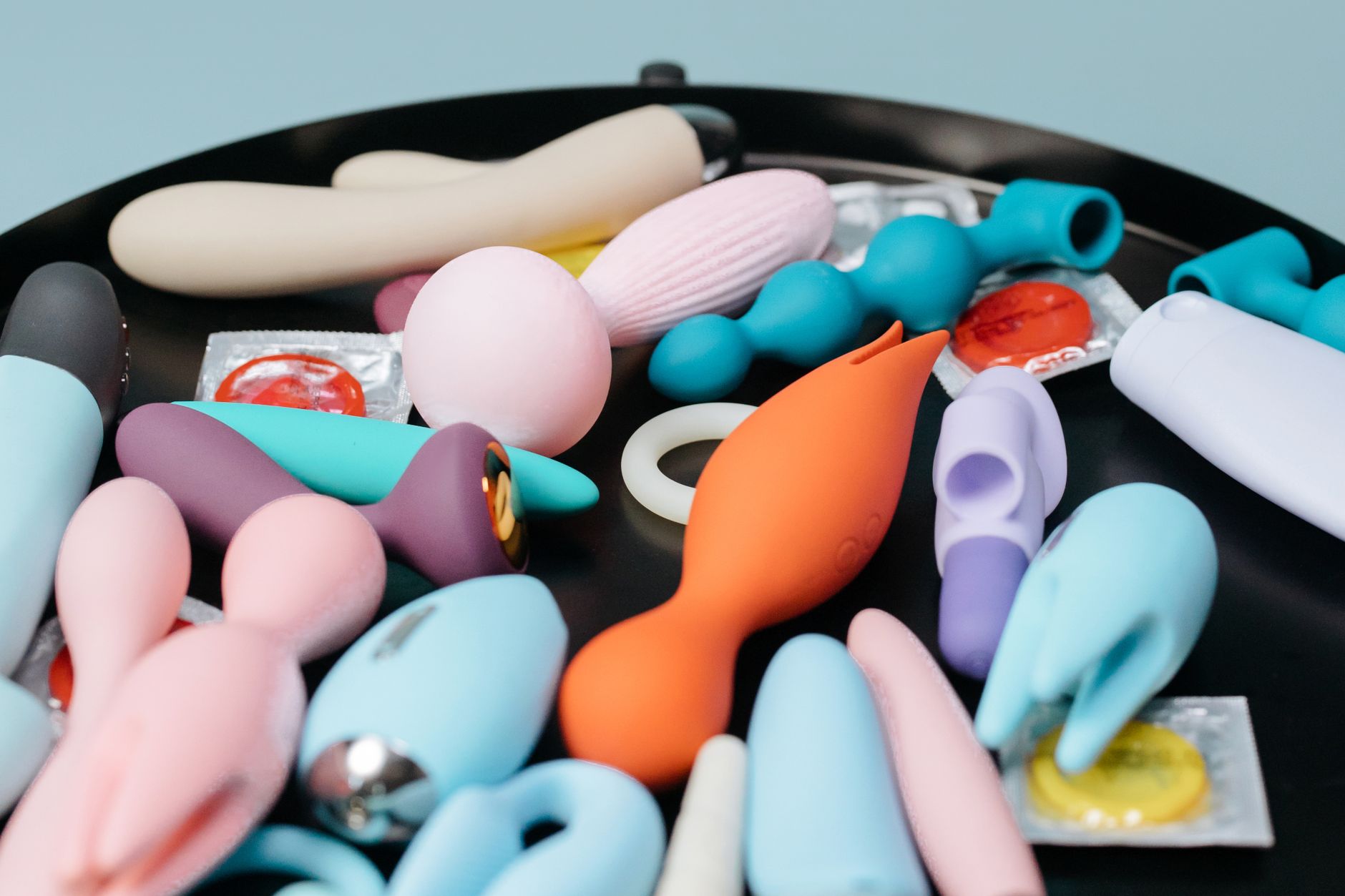 Two hands holding pink and blue silicone vibrators, representing tools for reconnecting with body and pleasure.