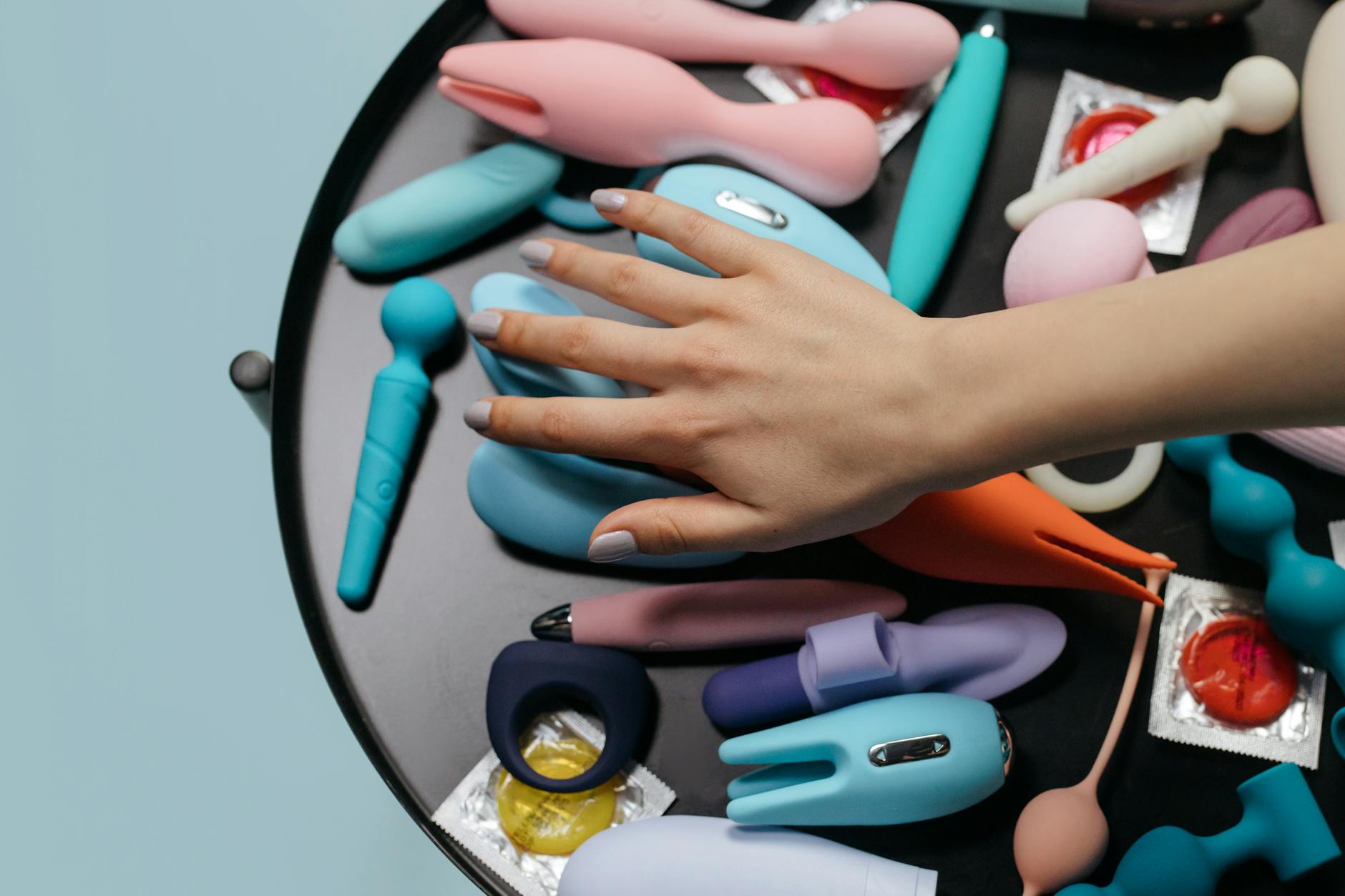 Two hands holding a sleek blue vibrator together against a purple background