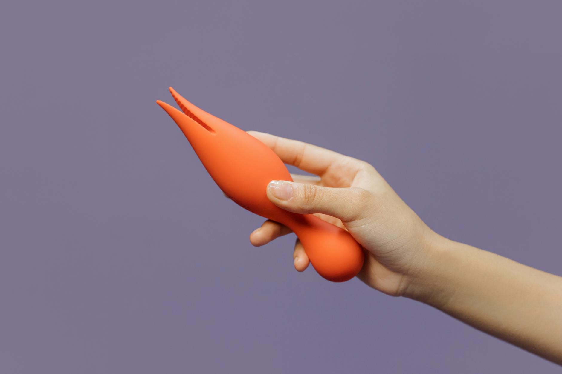 A hand holding a modern vibrator against a minimalistic purple backdrop, representing openness and vulnerability in new relationships