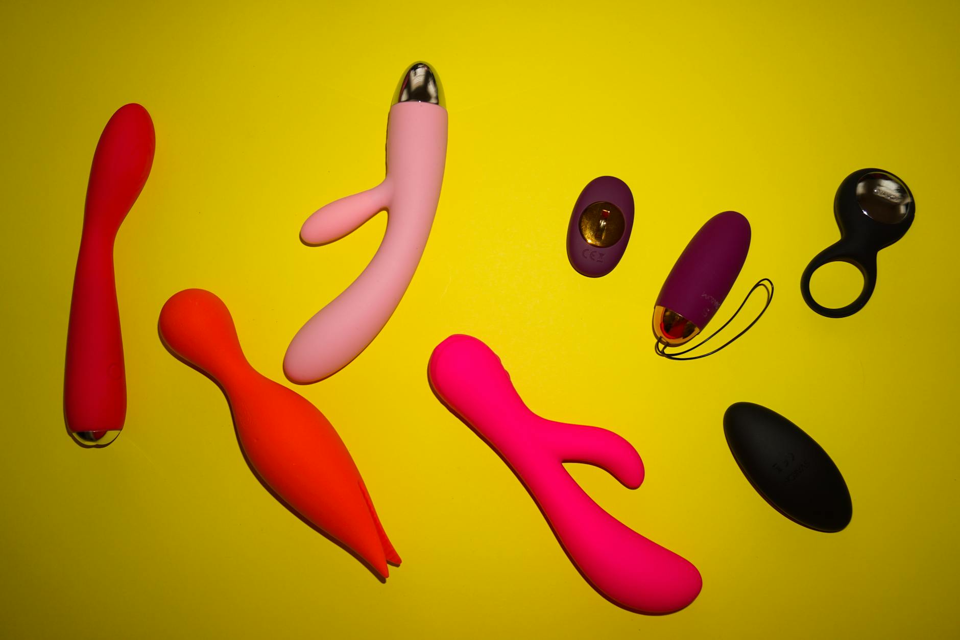 A hand holding a modern clitoral vibrator against a purple backdrop